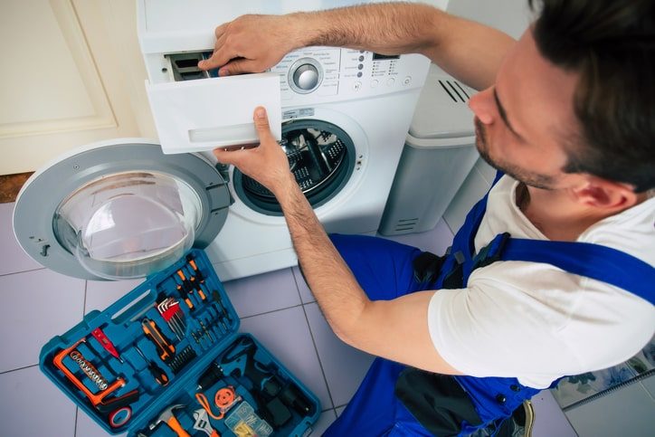Technician with a multimeter checking a washing machine motor